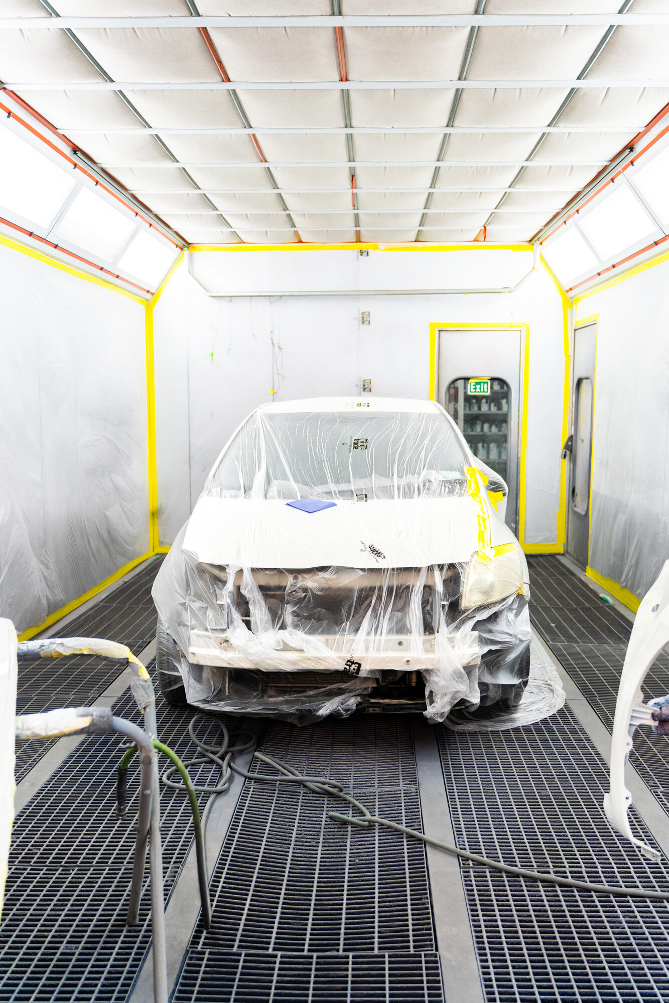 A vehicle masked and prepped under the lights of the Avon City Paint & Panel spray booth